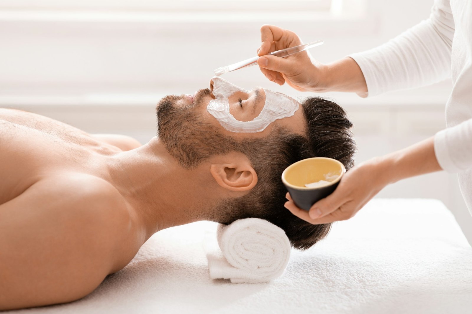 Bearded man getting face treatment at spa salon